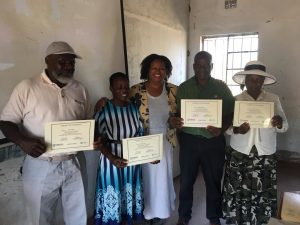 Above Promotions in Zimbabwe, holding certificates, posing for a group photo in front of a wall and window—celebrating their achievements at a digital marketing agency.