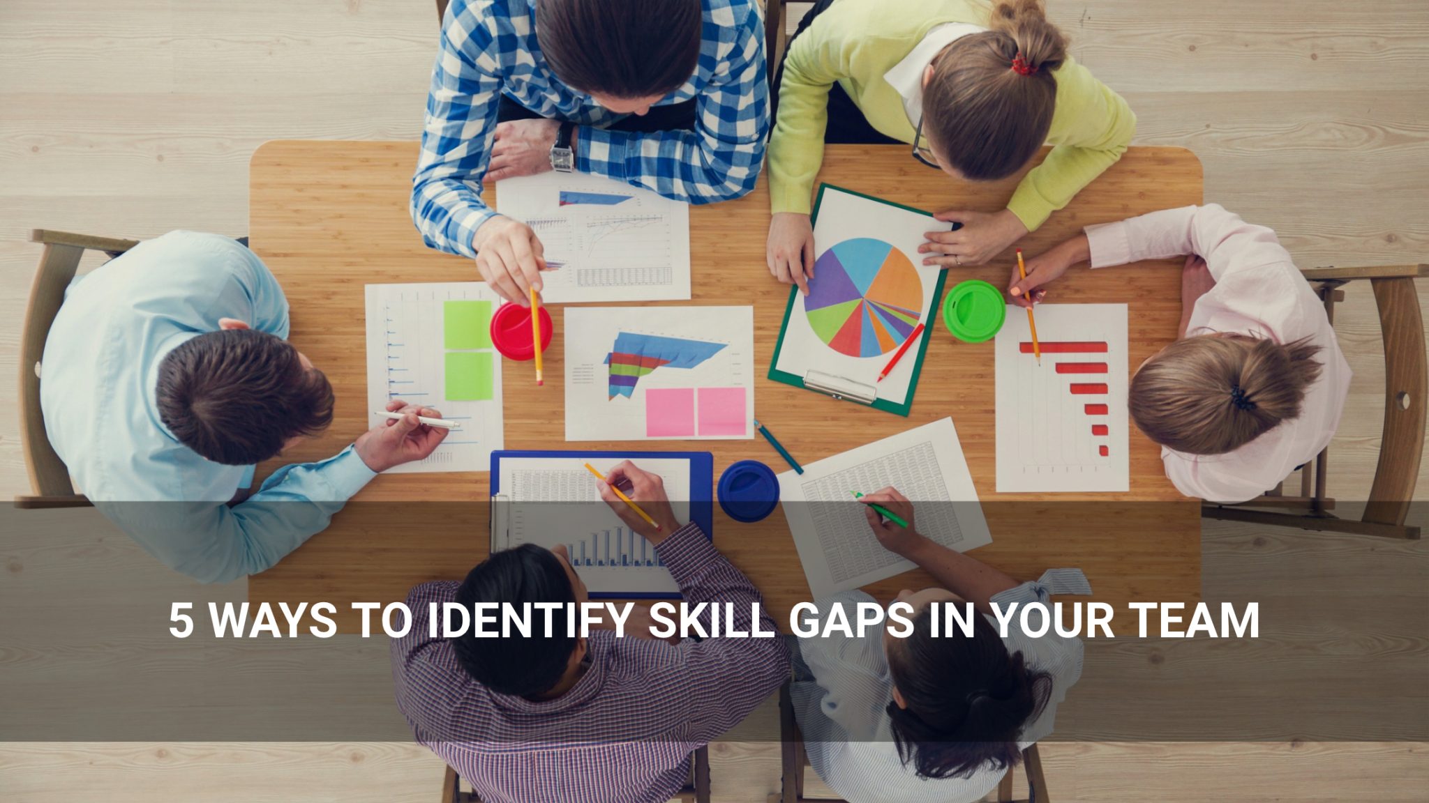 5 Ways to Identify Skill Gaps in Your Team — people reviewing charts and documents together. - Above Promotions