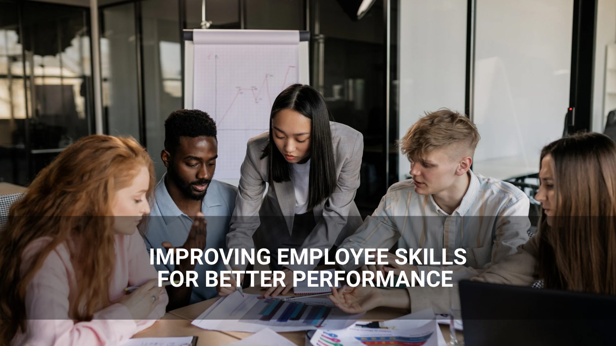Five people collaborate around a table with documents and a laptop, focusing on enhancing employee skills. Text overlay reads: "Improving Employee Skills for Better Performance.