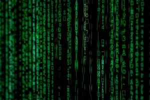 Green digital code streams down a black screen, reminiscent of the iconic "Matrix" film style, with vertical lines of numbers and symbols creating a futuristic, computer-generated effect.