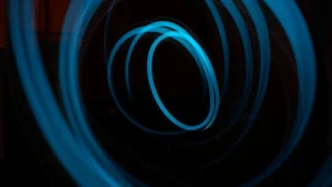 Blue neon light trails form overlapping circular patterns against a dark background.