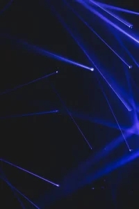 Blue laser beams shining in a dark space, creating intersecting lines.