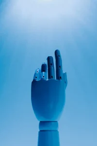 A blue robotic hand is raised against a bright blue background with rays of light shining from above.