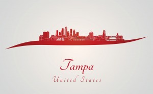 An artistic red silhouette of Tampa’s skyline with prominent buildings, set against a light grey background, accompanied by the words "Tampa United States" in elegant script, designed for social media use.